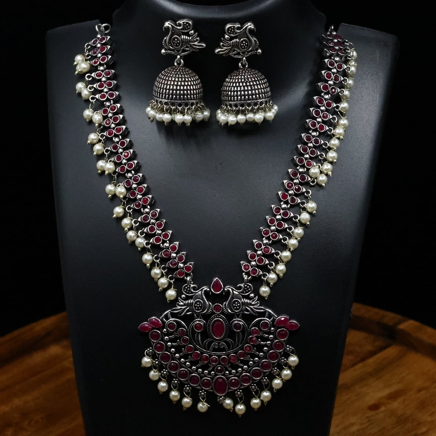 German Silver - Plated Necklace and Jhumka Earrings Embellished with Brilliant Red Gemstones and Gleaming Pearl Drops - The Soul Jewellery